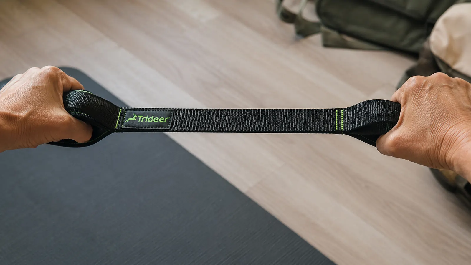 Close-up of hands using the loops on a Trideer stretch strap to pull a leg upward